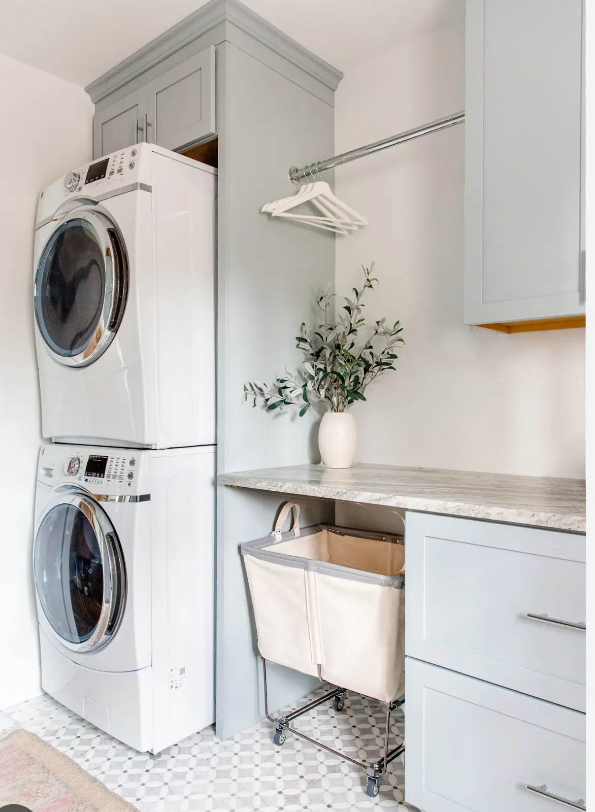 Laundry room concept with stacked appliances, upper cabinetry, counter space, and hanging storage.